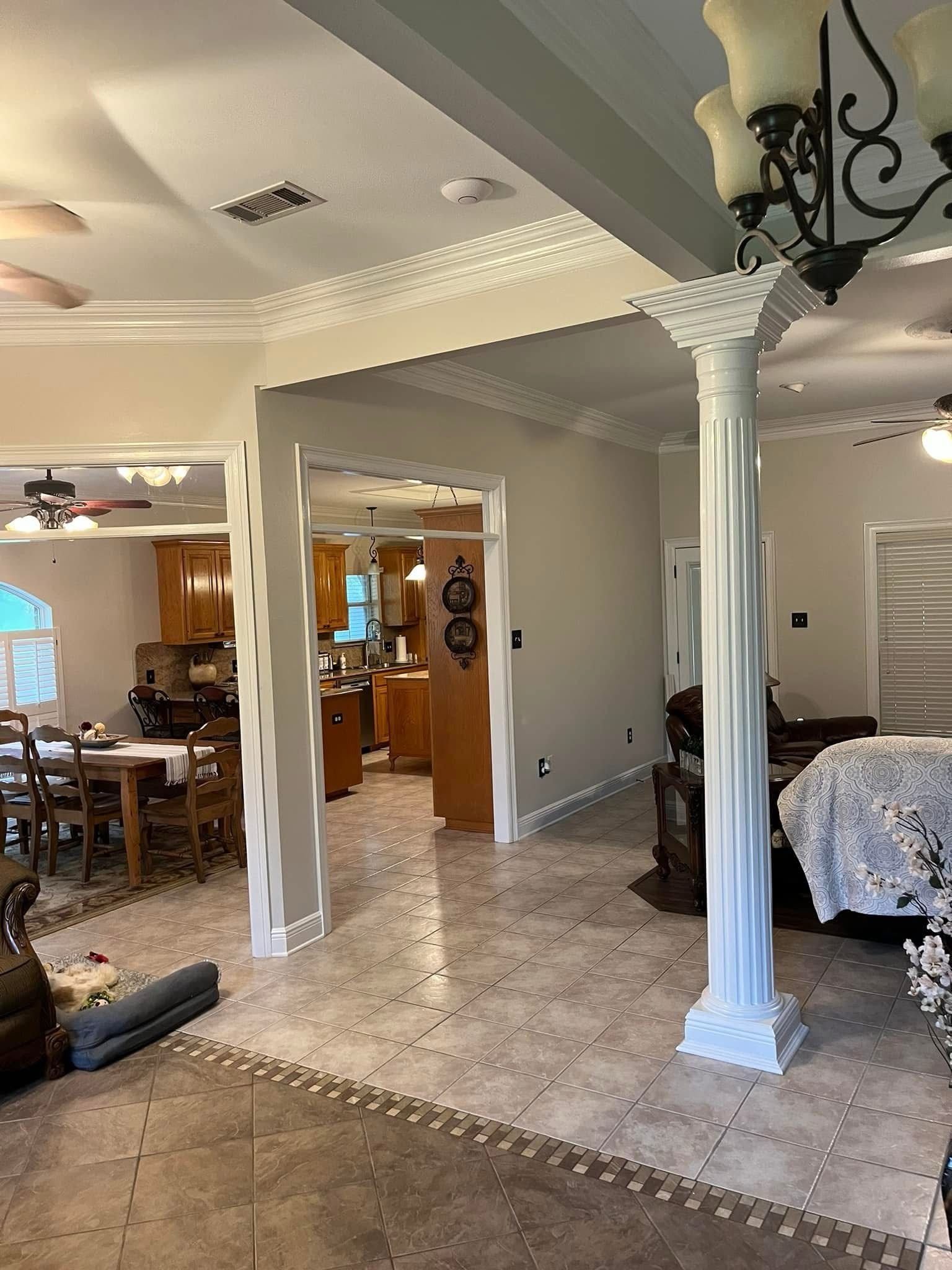 Interior view of a home with a column, open doorways, and a view into the kitchen.