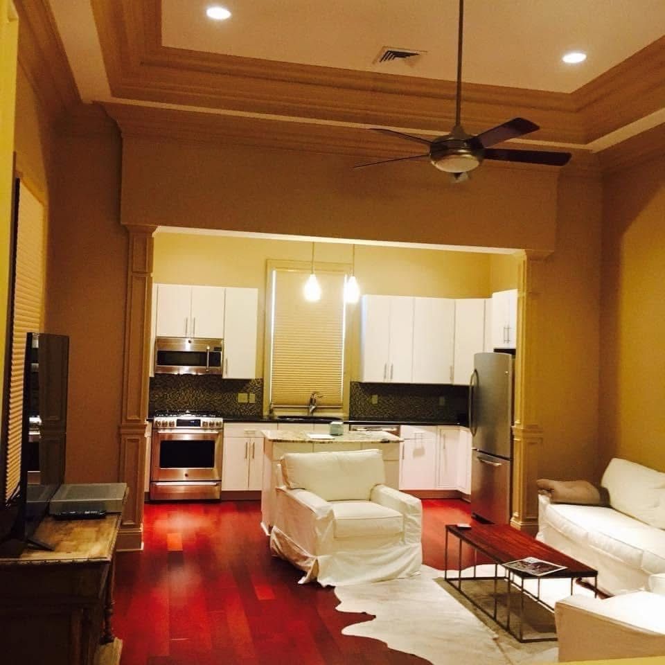 Living room with open kitchen; white sofas, dark red floor, cowhide rug.