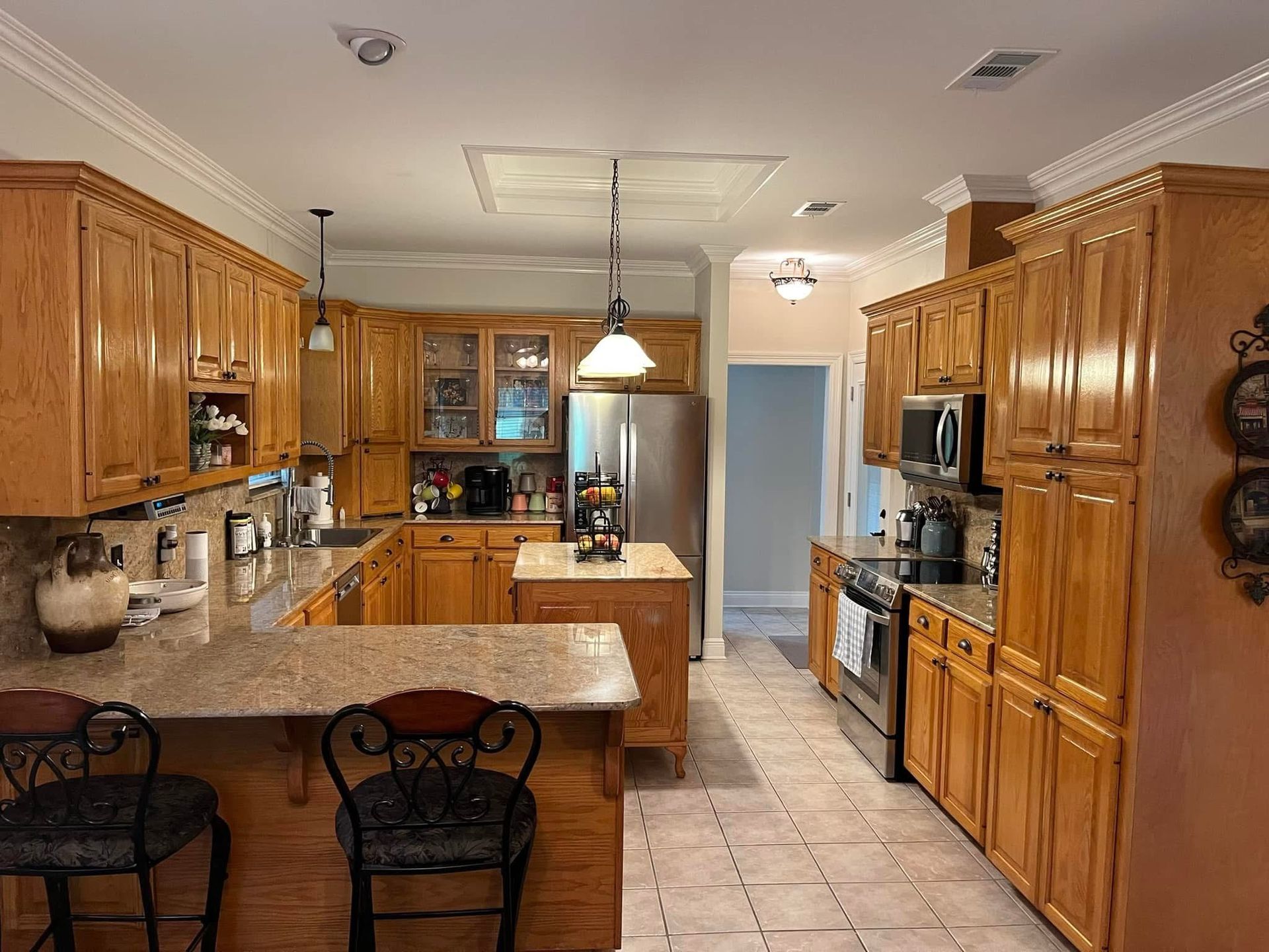 Spacious kitchen with wood cabinets, island, and stainless steel appliances. Beige countertops and tiled floor.