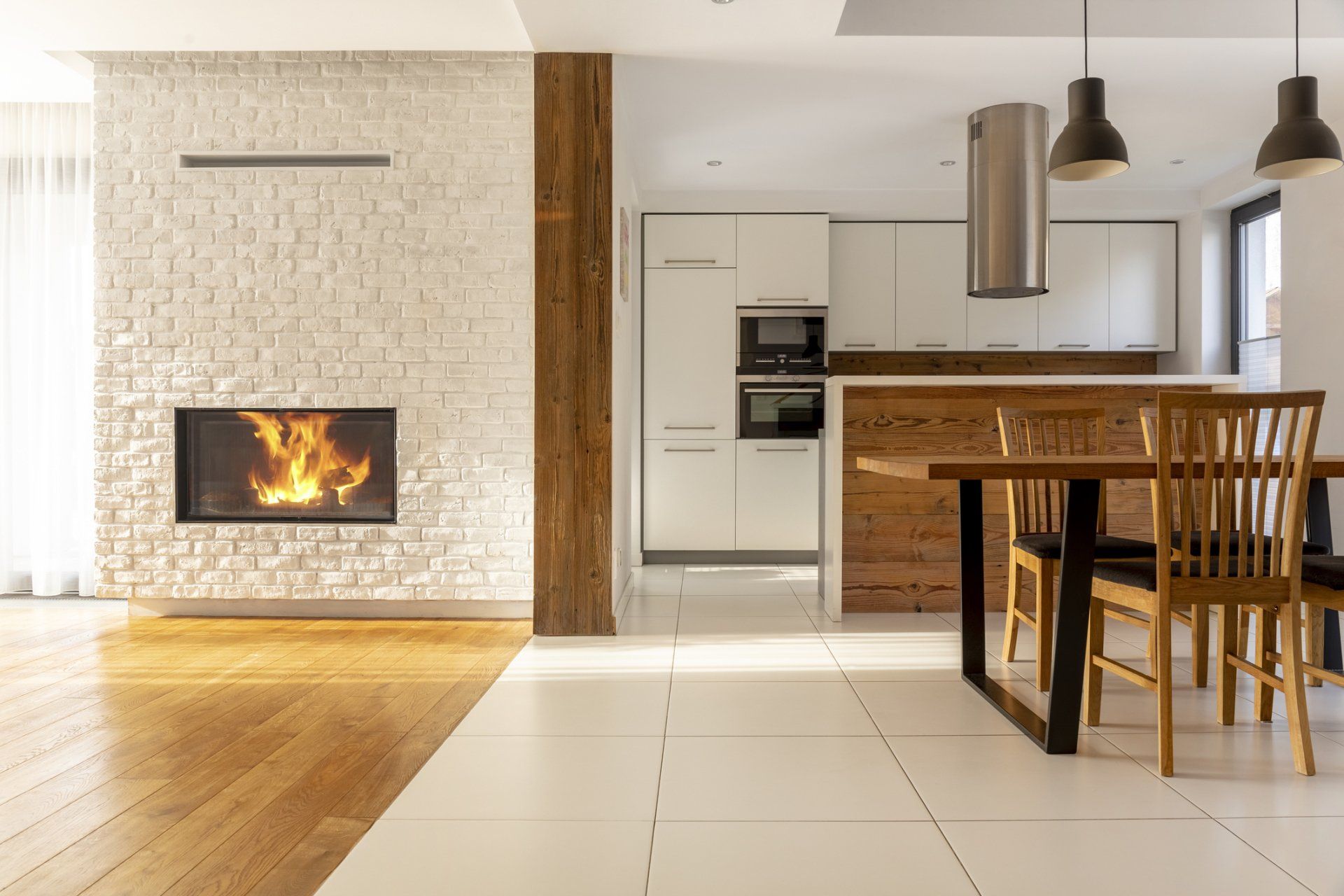 Modern open-concept home with fireplace, kitchen, and dining area. Warm wood and bright white accents.