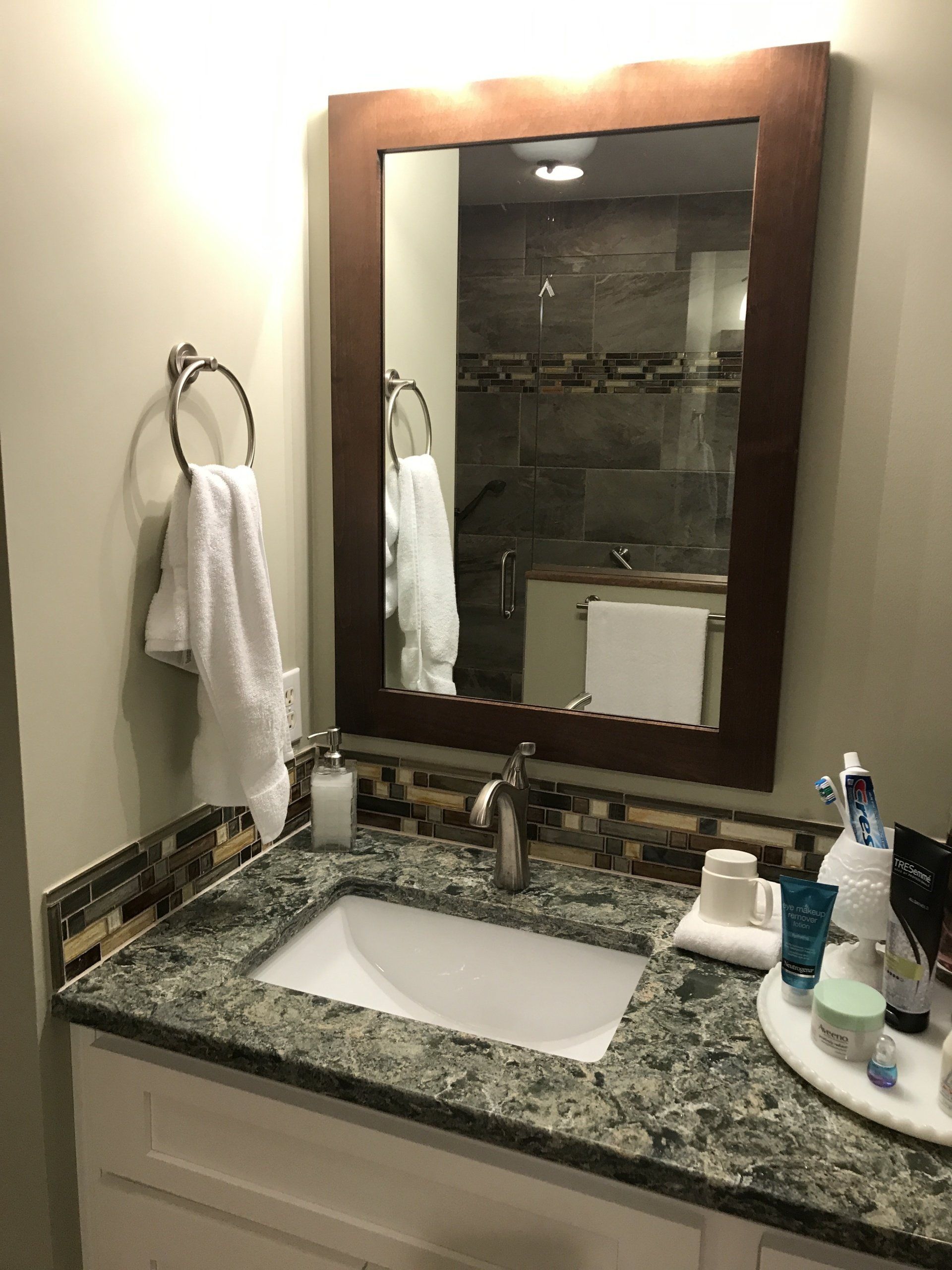 Bathroom with a vanity, sink, mirror, towel rack, and toiletries.