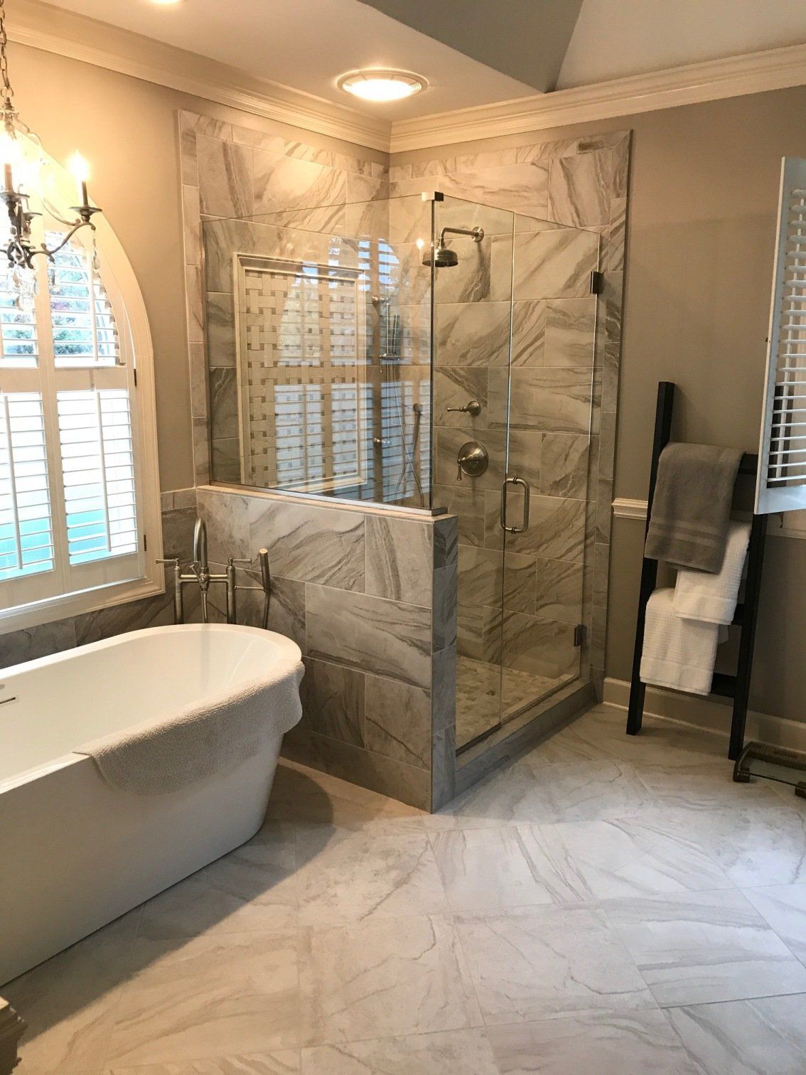 Spacious bathroom with a white tub, glass shower, and patterned tile flooring.