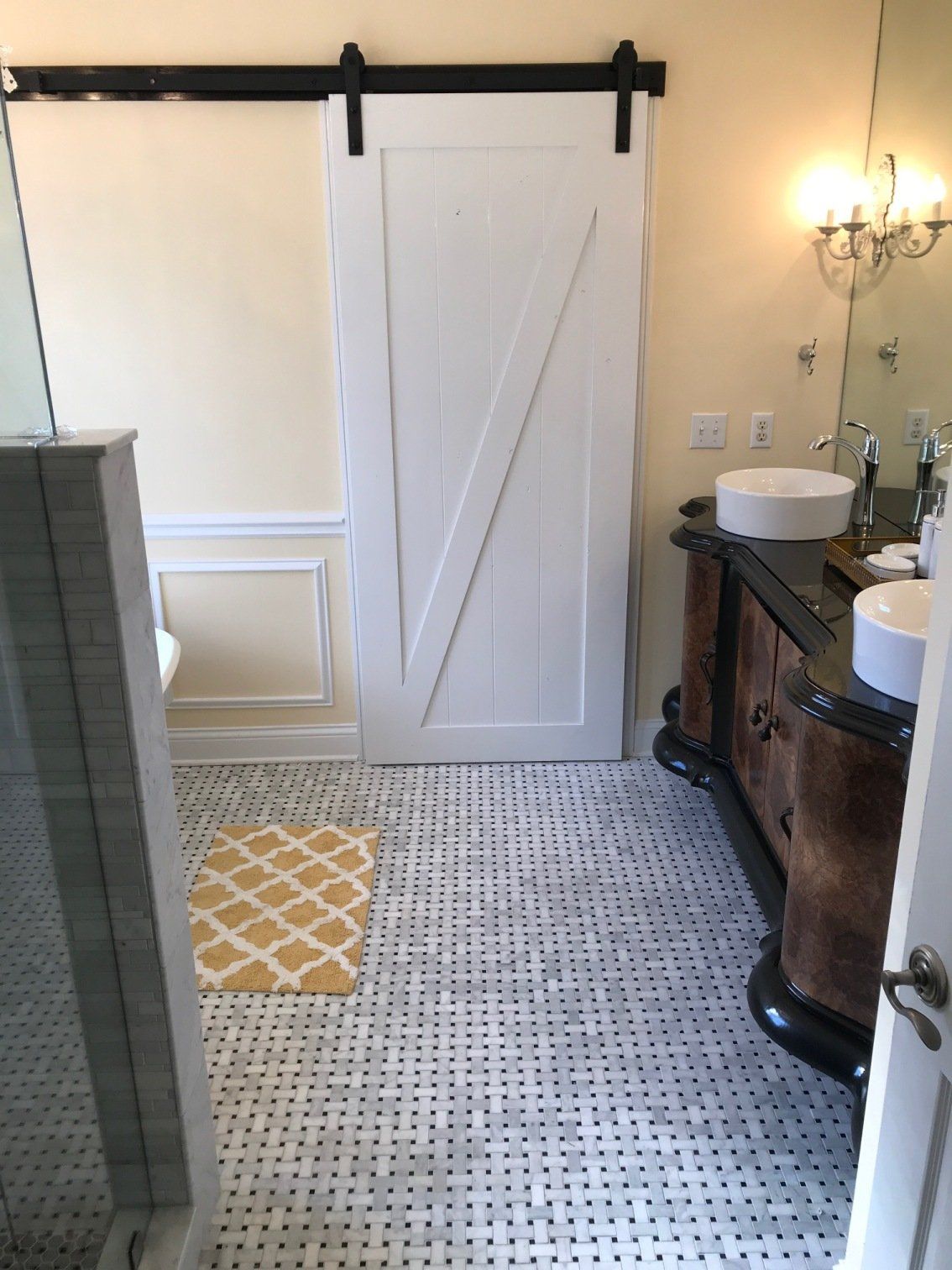 Bathroom with white barn door, marble tile floor, and ornate vanity.