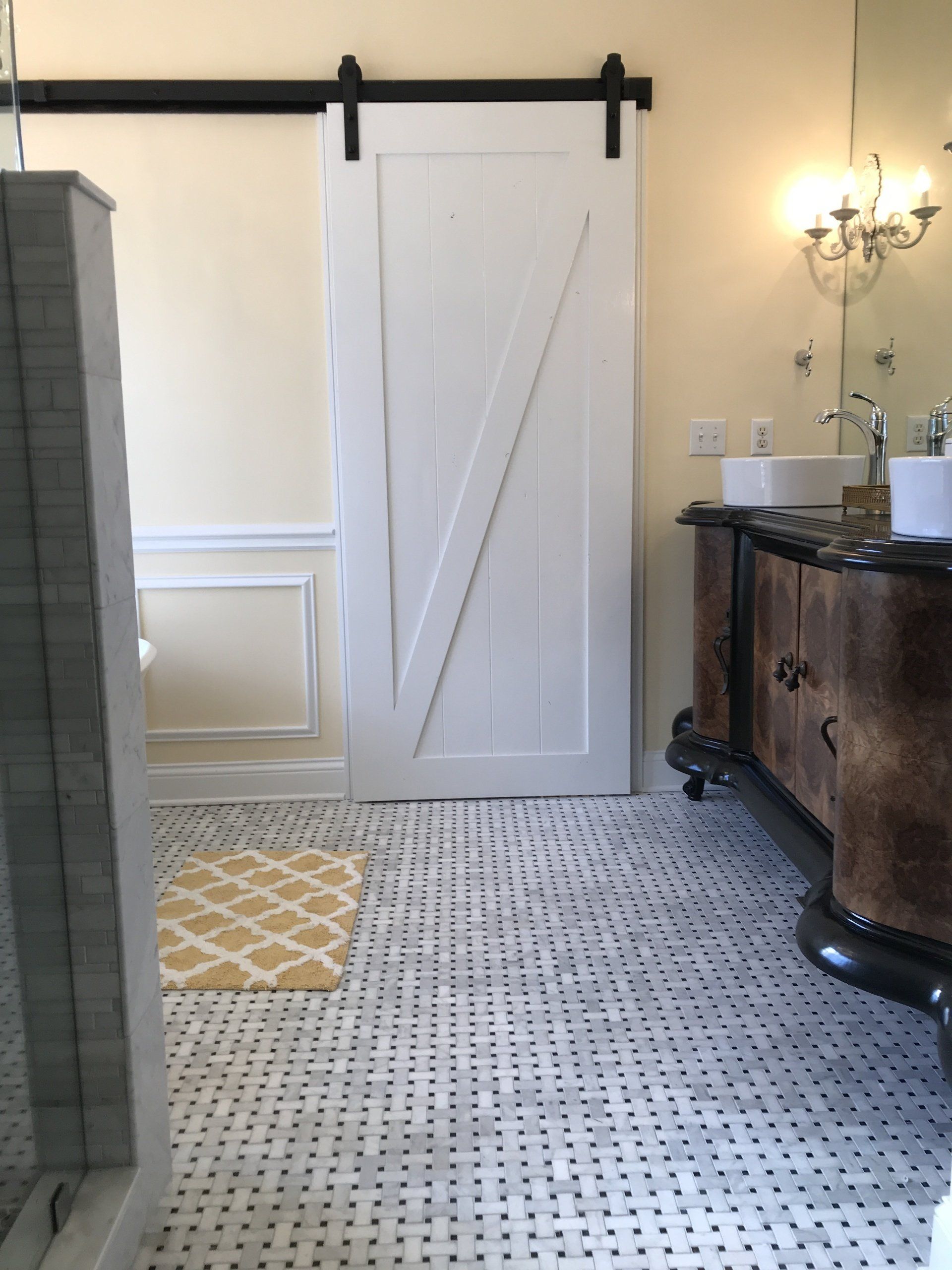 Bathroom with a white barn door, vanity, and tiled floor.