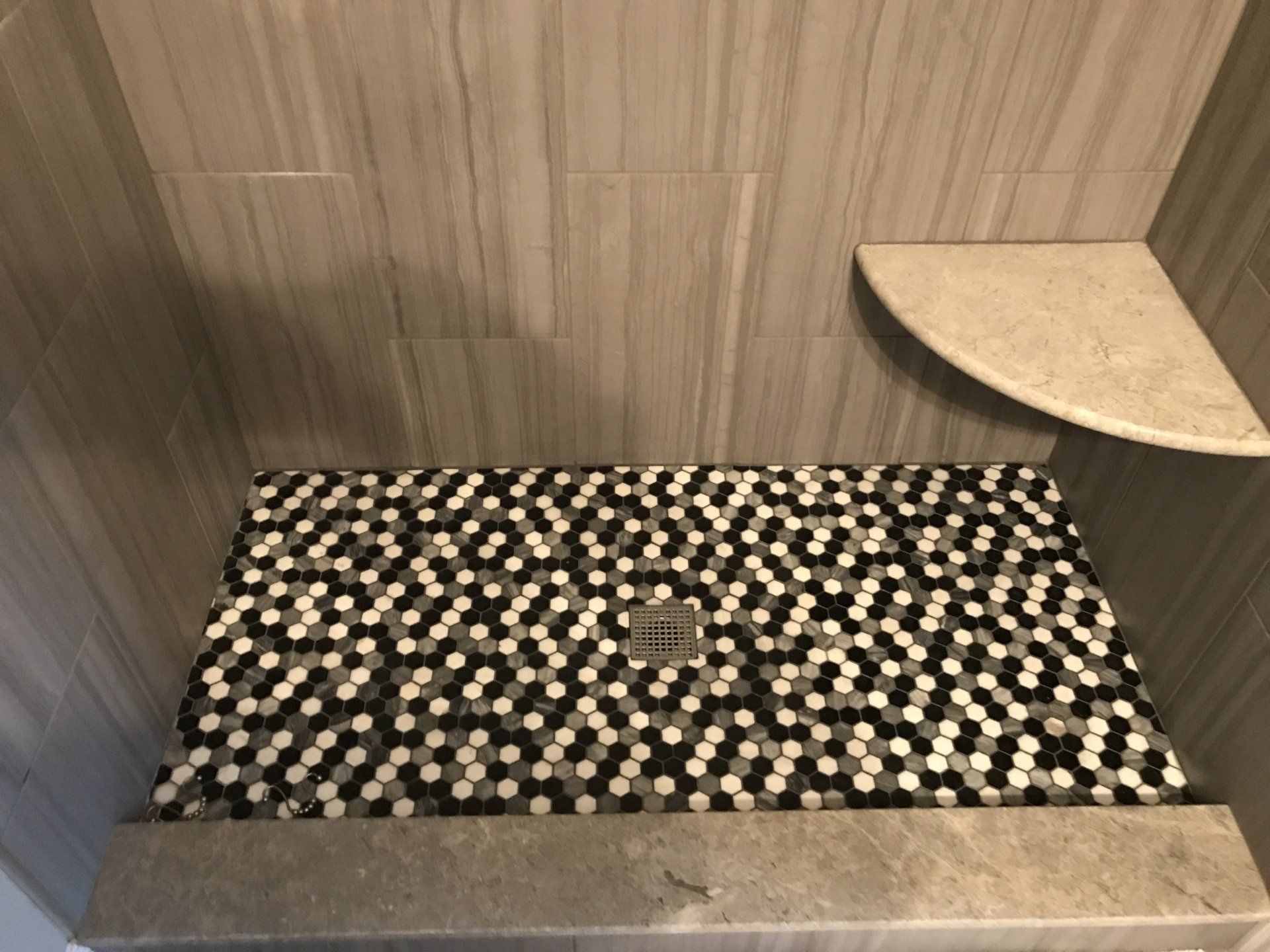 Shower with gray walls, patterned floor tiles, and a corner shelf.
