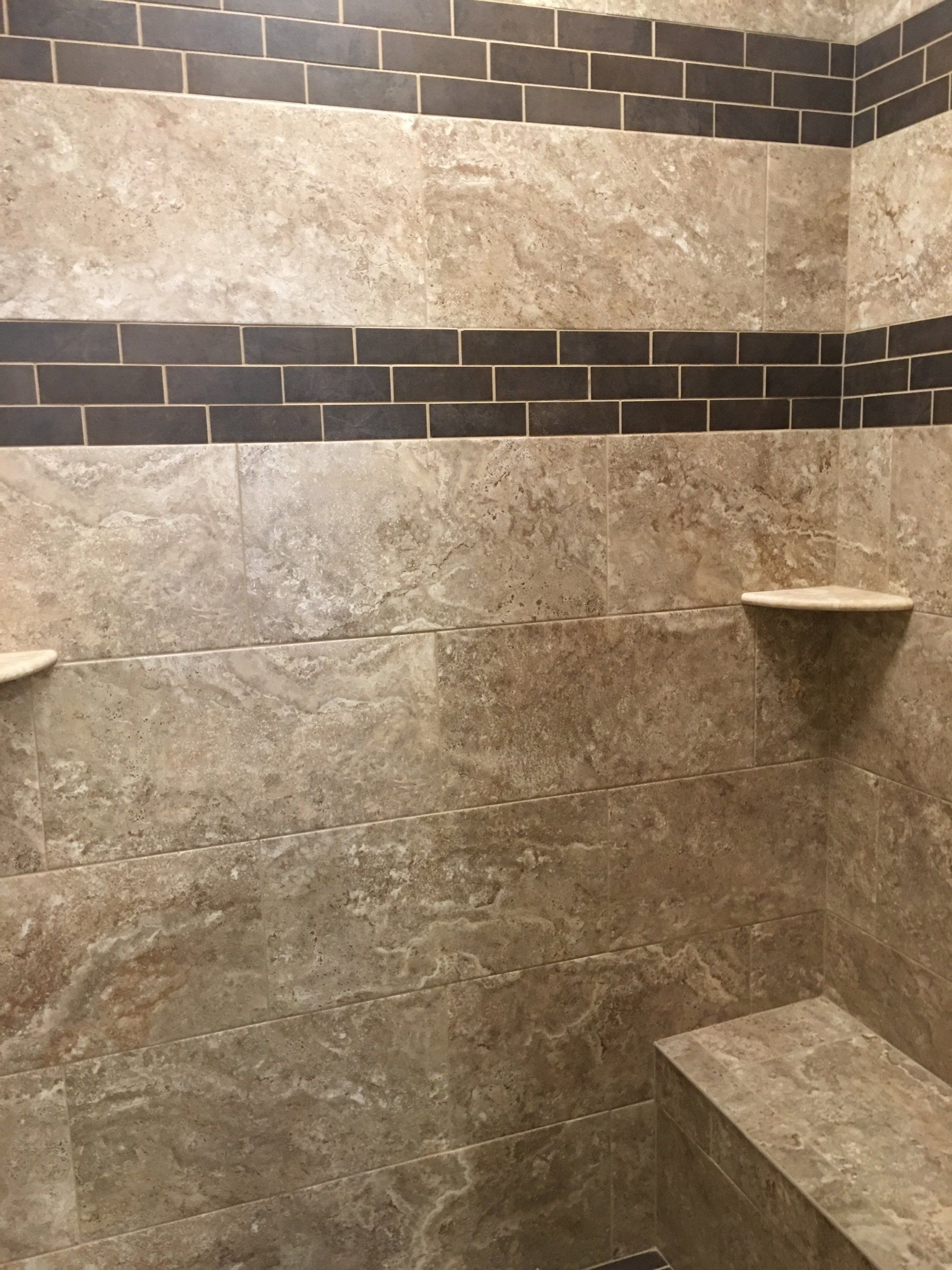 Shower with tan tile, brown brick accent, built-in bench and shelves.