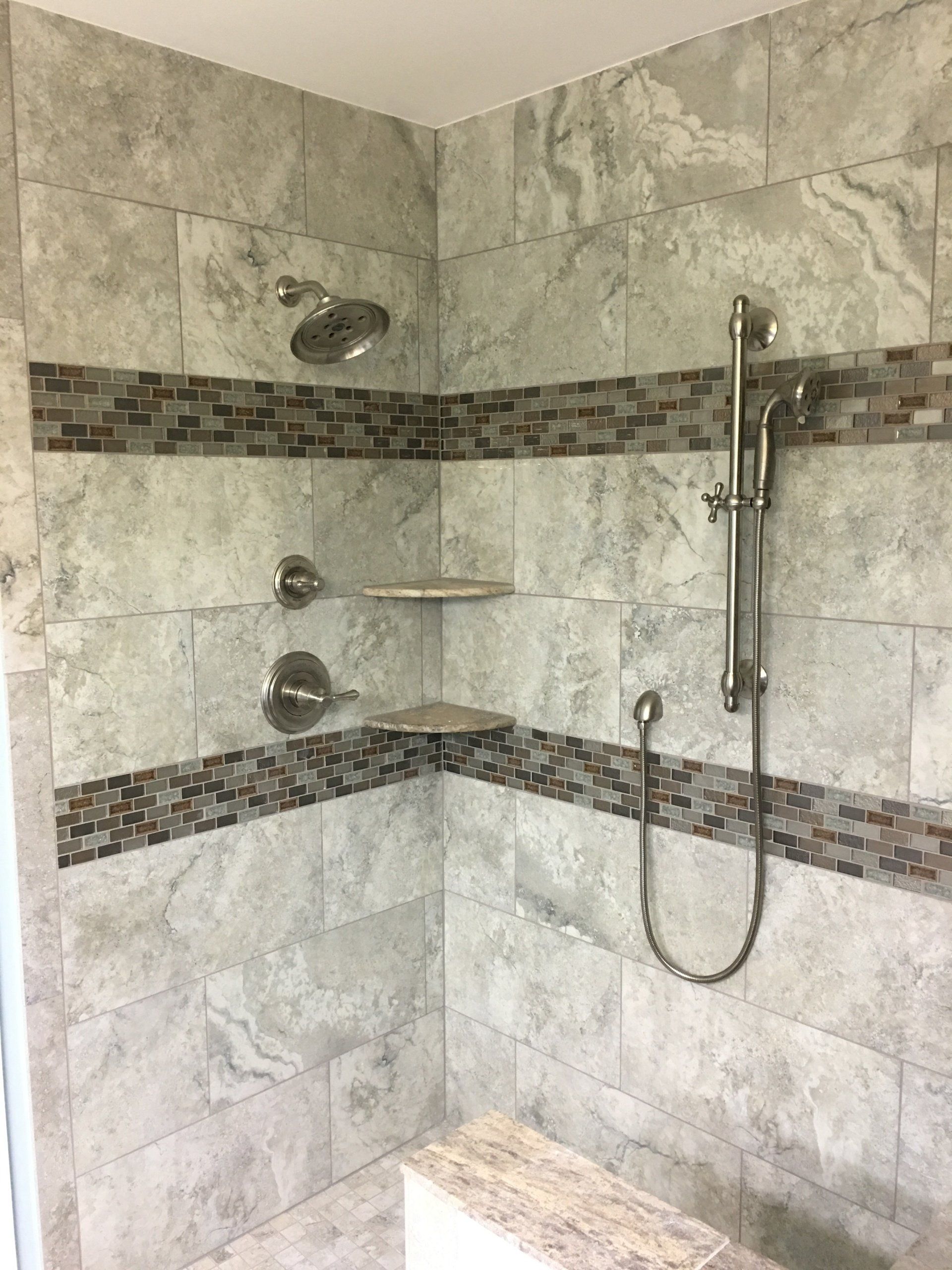 Tiled corner shower with gray stone-like tiles, a brown mosaic border, and chrome shower fixtures.