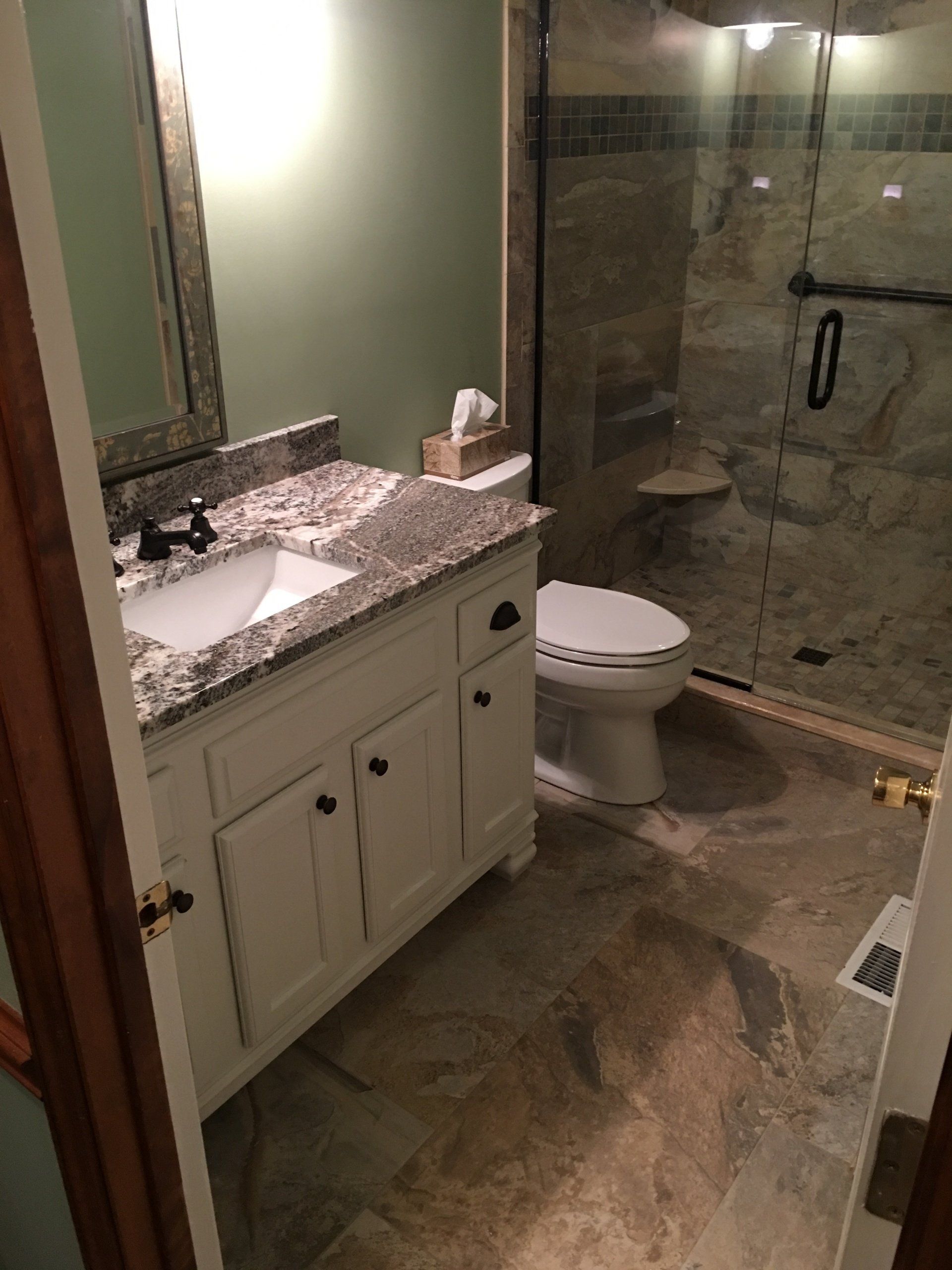 Bathroom with white vanity, granite countertop, shower with stone walls, and a toilet.