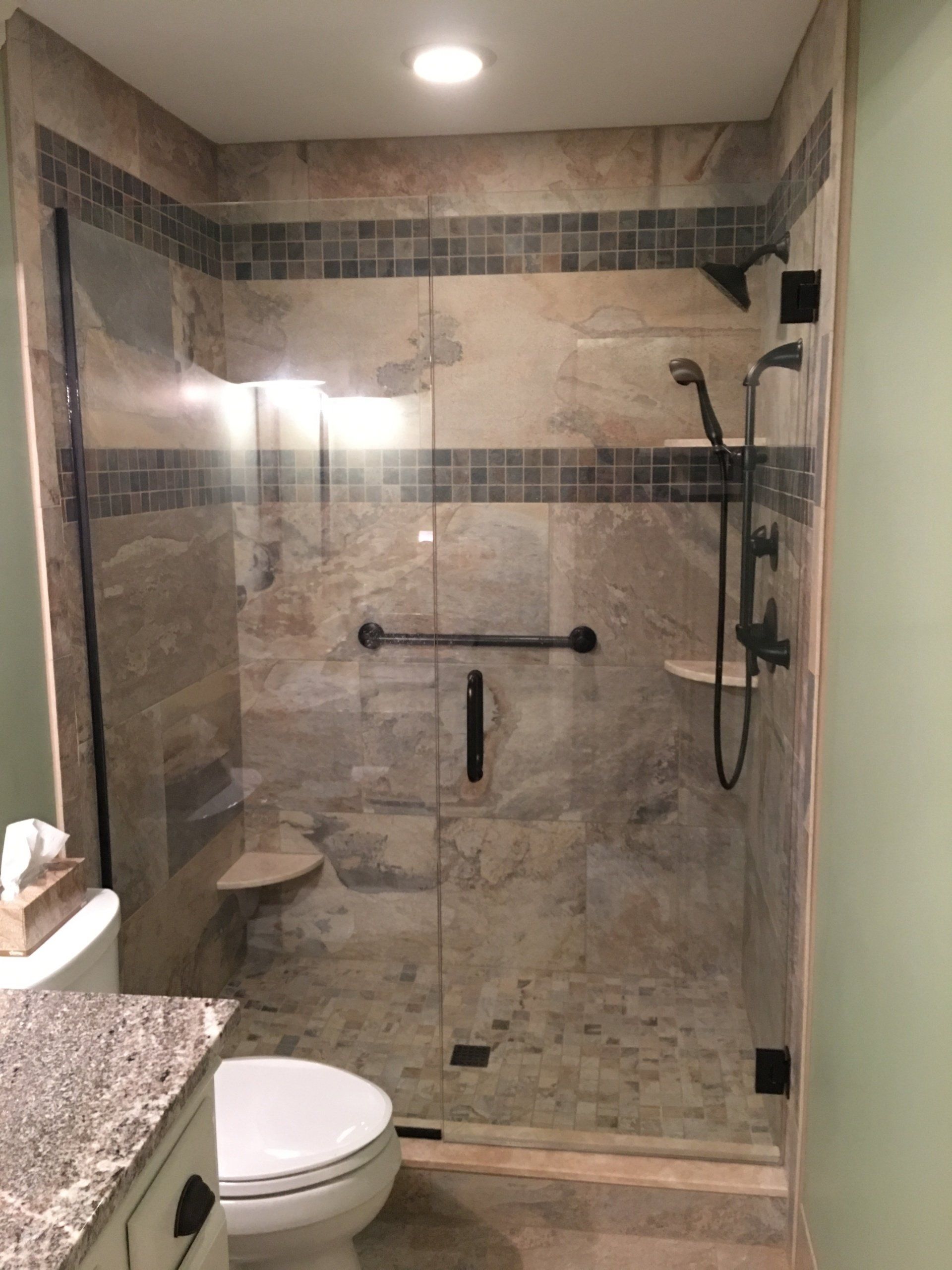 Bathroom with a glass shower, light stone tile, and dark bronze fixtures.