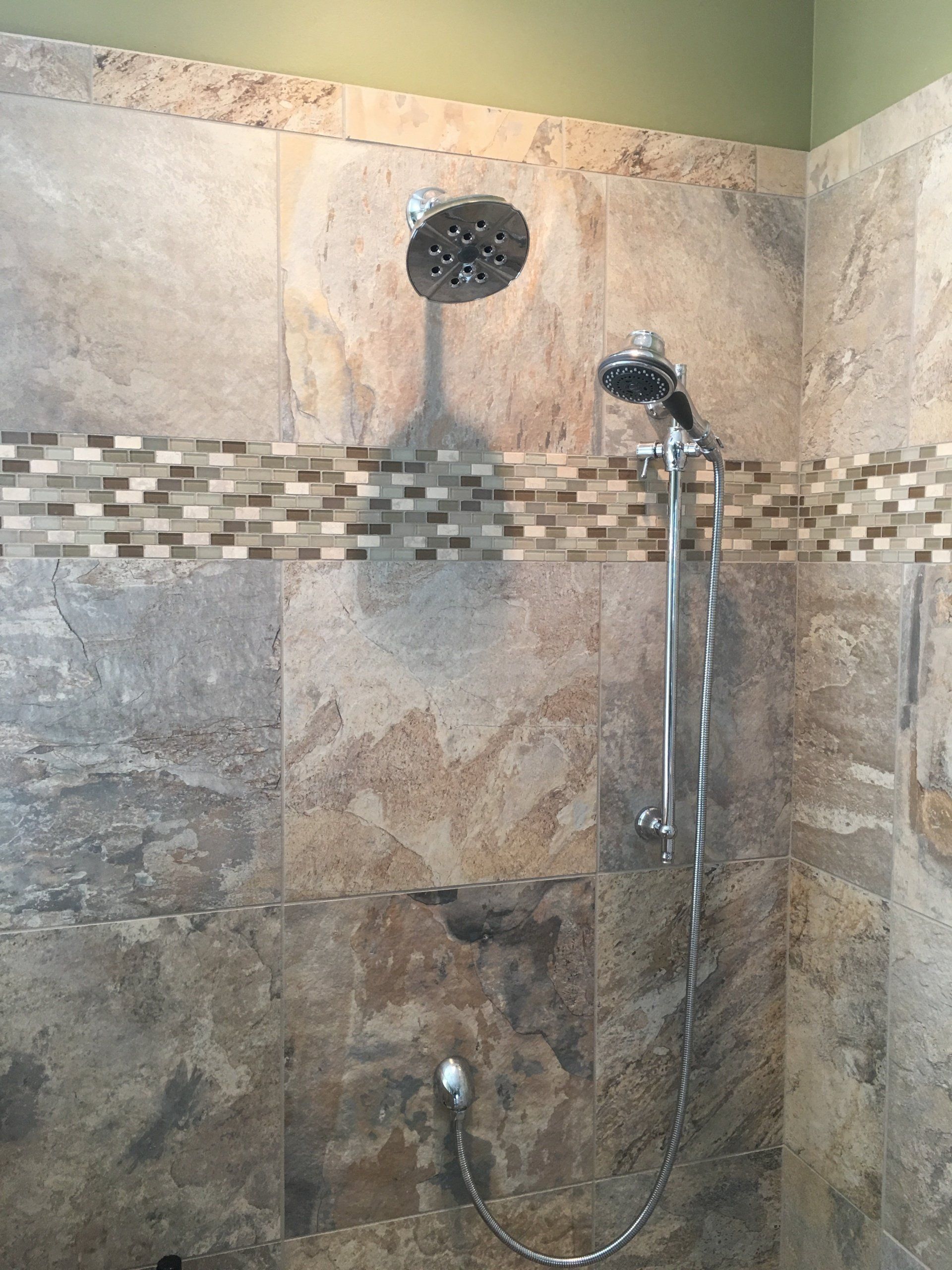 Shower with two shower heads and decorative tile.