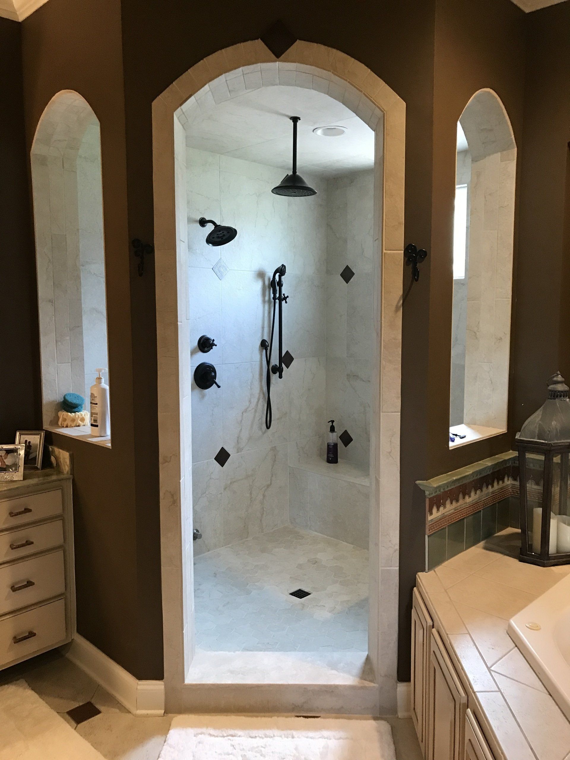 Bathroom with stone archway shower, brown walls, and cream-colored cabinets.