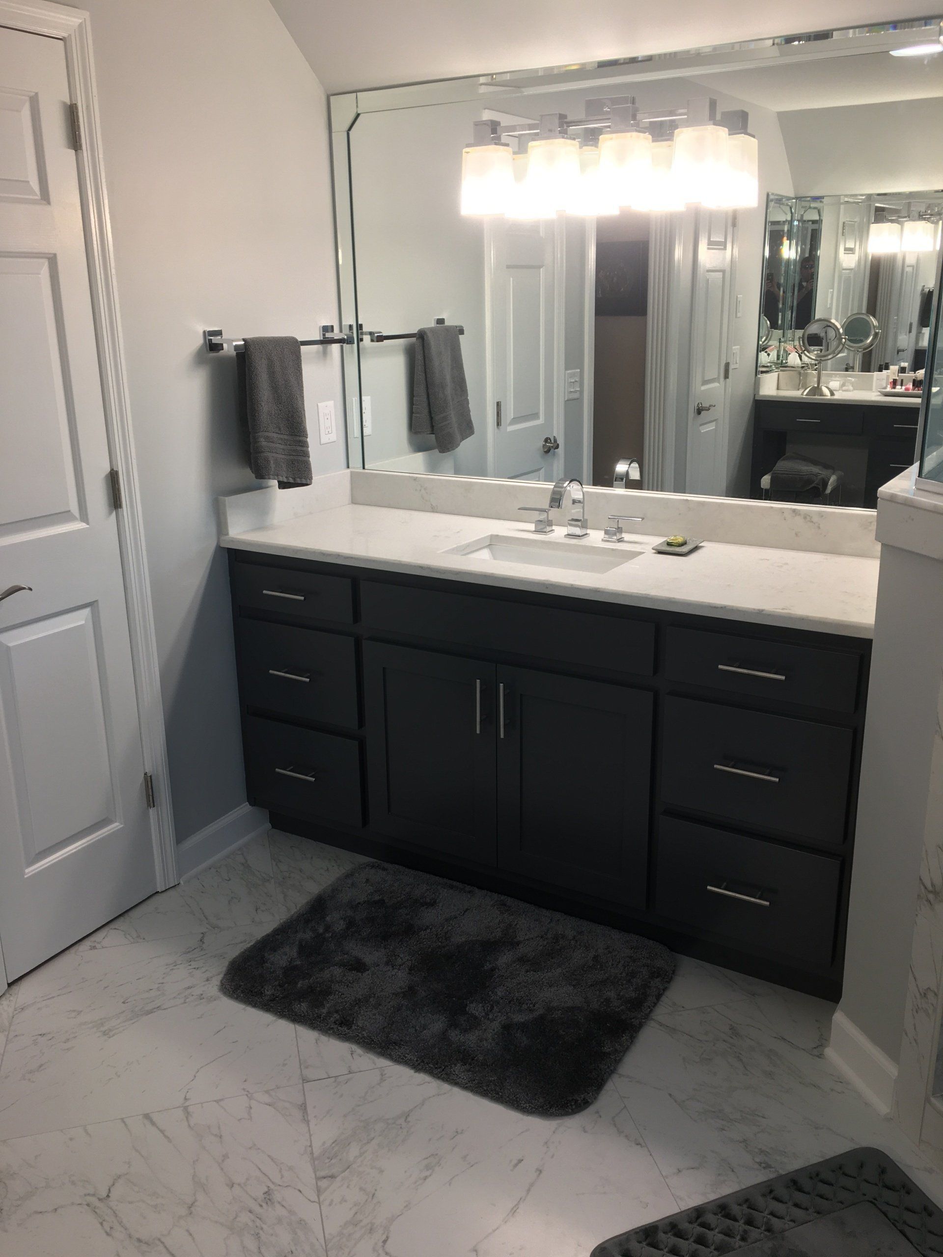 Bathroom with dark gray vanity, white countertop, and large mirror.