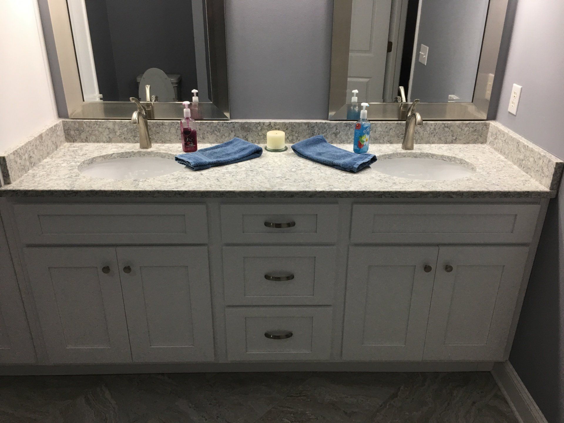 White double vanity with gray granite countertop, two sinks, mirrors, and towels.