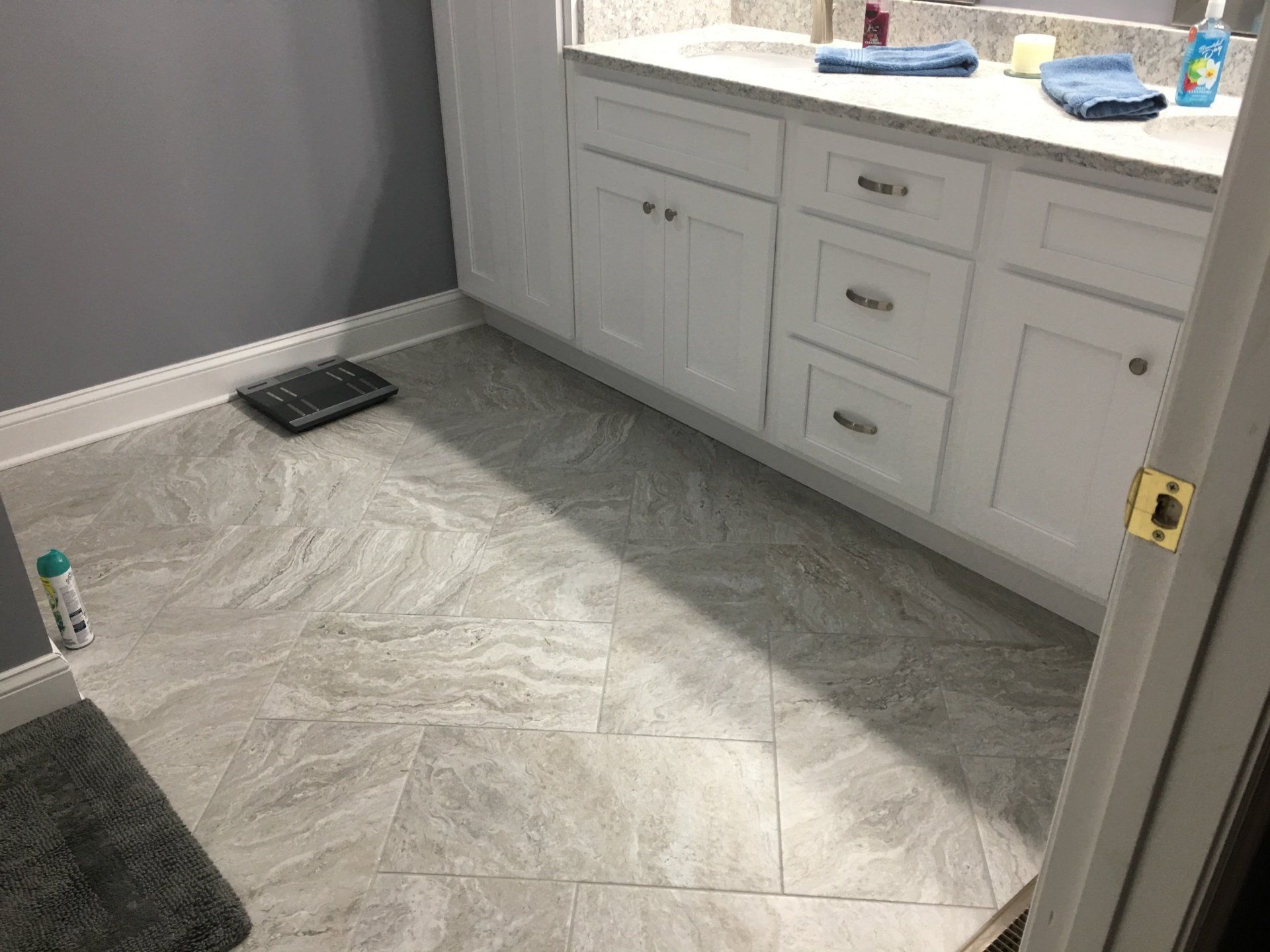 Bathroom with gray tile floor, white cabinets, and gray walls.