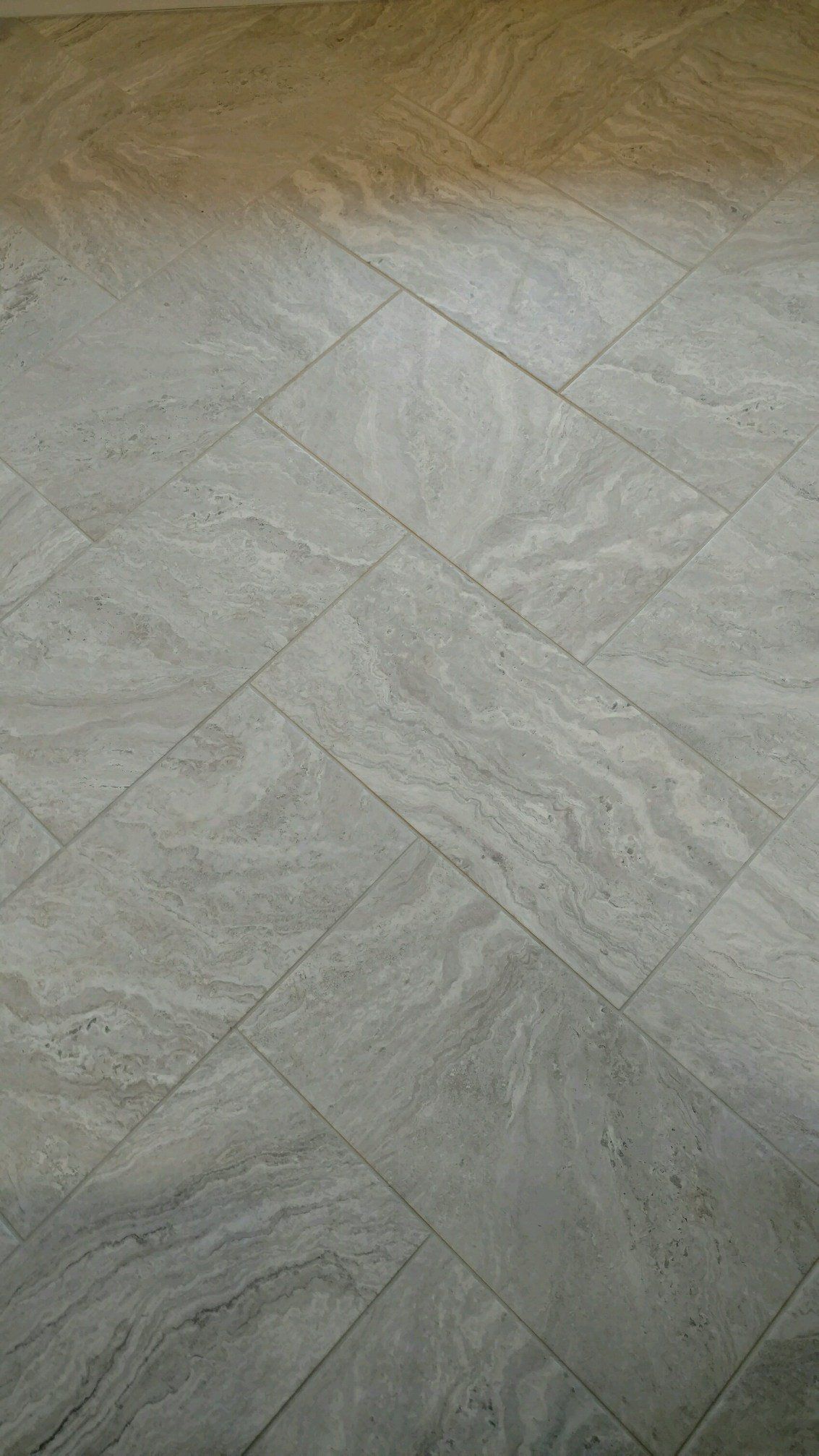 Gray and light brown tiled floor, diagonally laid pattern.