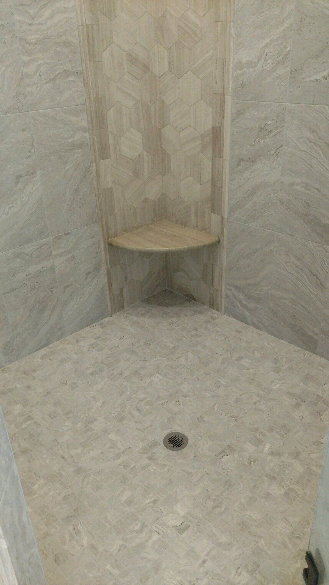 Shower stall with beige tile and a corner shelf.