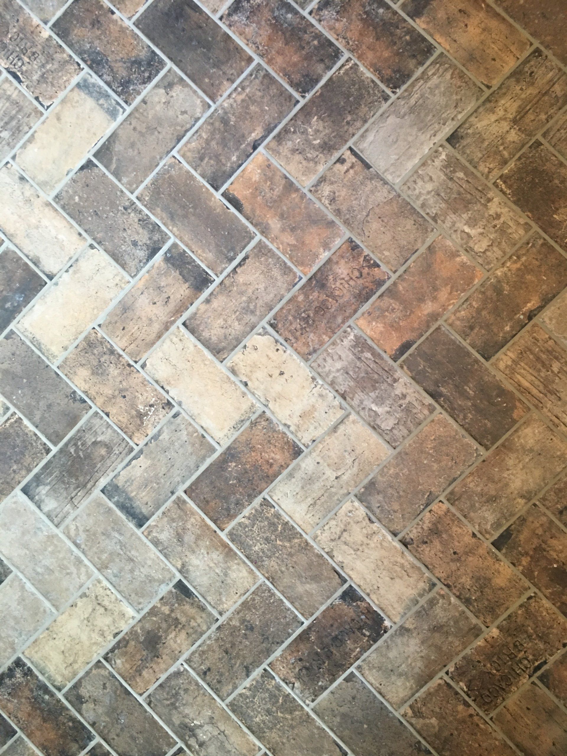 Herringbone pattern floor tiling in shades of brown, beige, and gray.