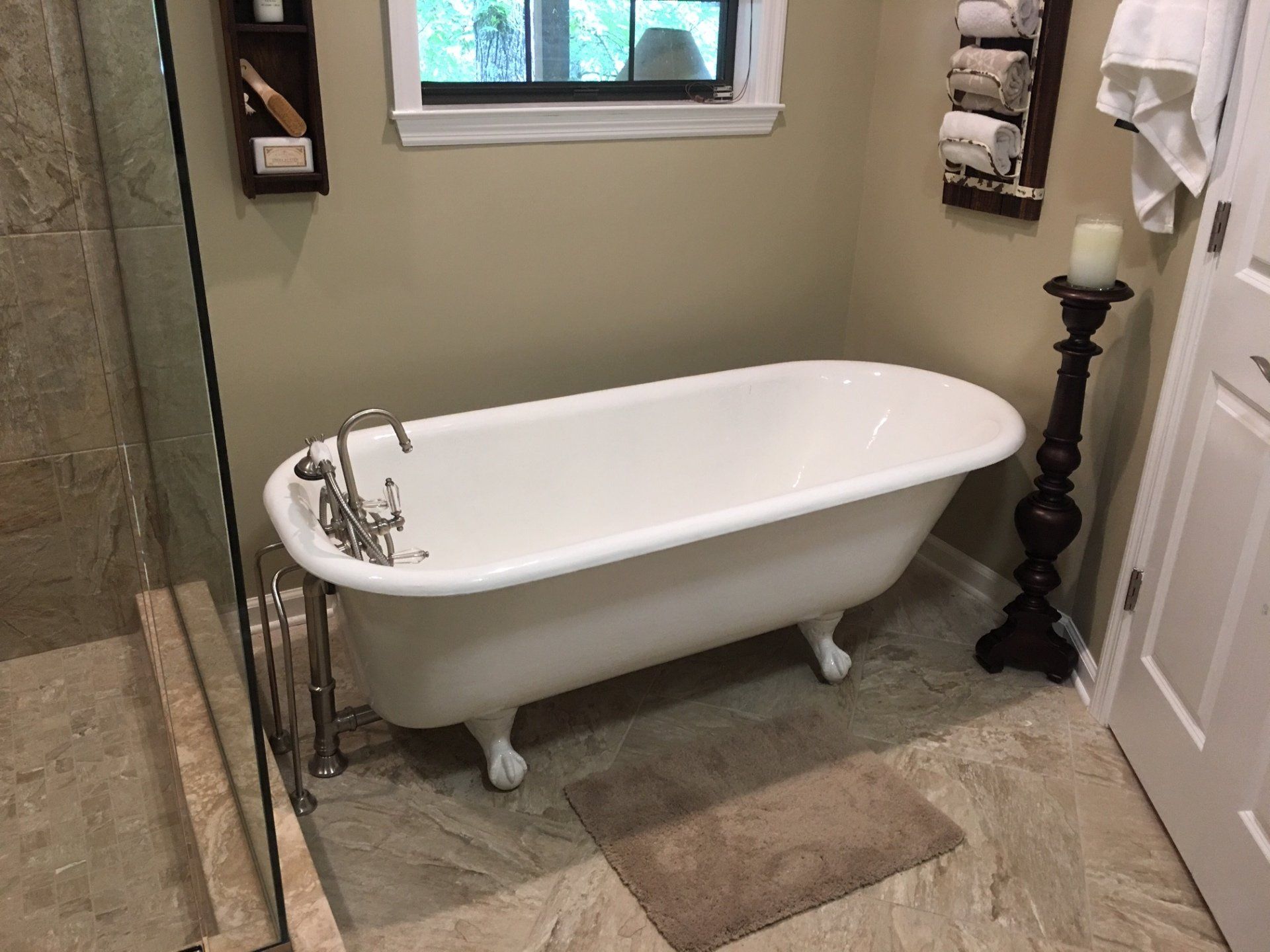 White clawfoot bathtub in a bathroom with beige walls and tile, a window, and towels.