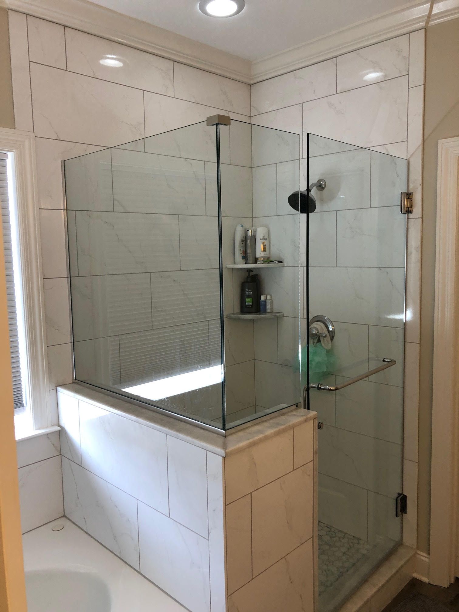 Modern bathroom with a glass shower enclosure, white tile walls, and a bathtub.