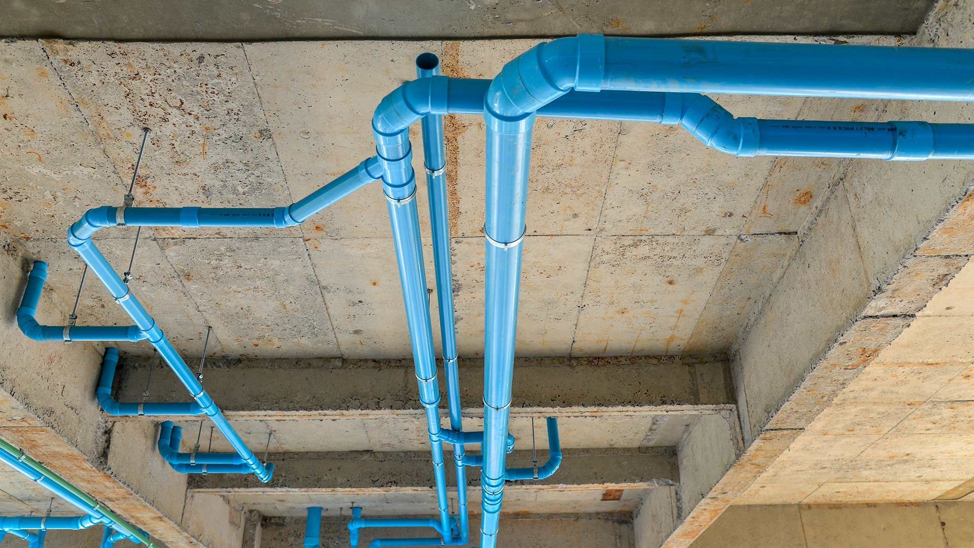 A bunch of blue pipes are hanging from the ceiling of a building.