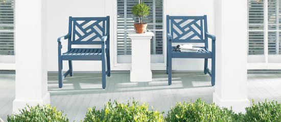 Two blue chairs are sitting on a porch next to a potted plant.