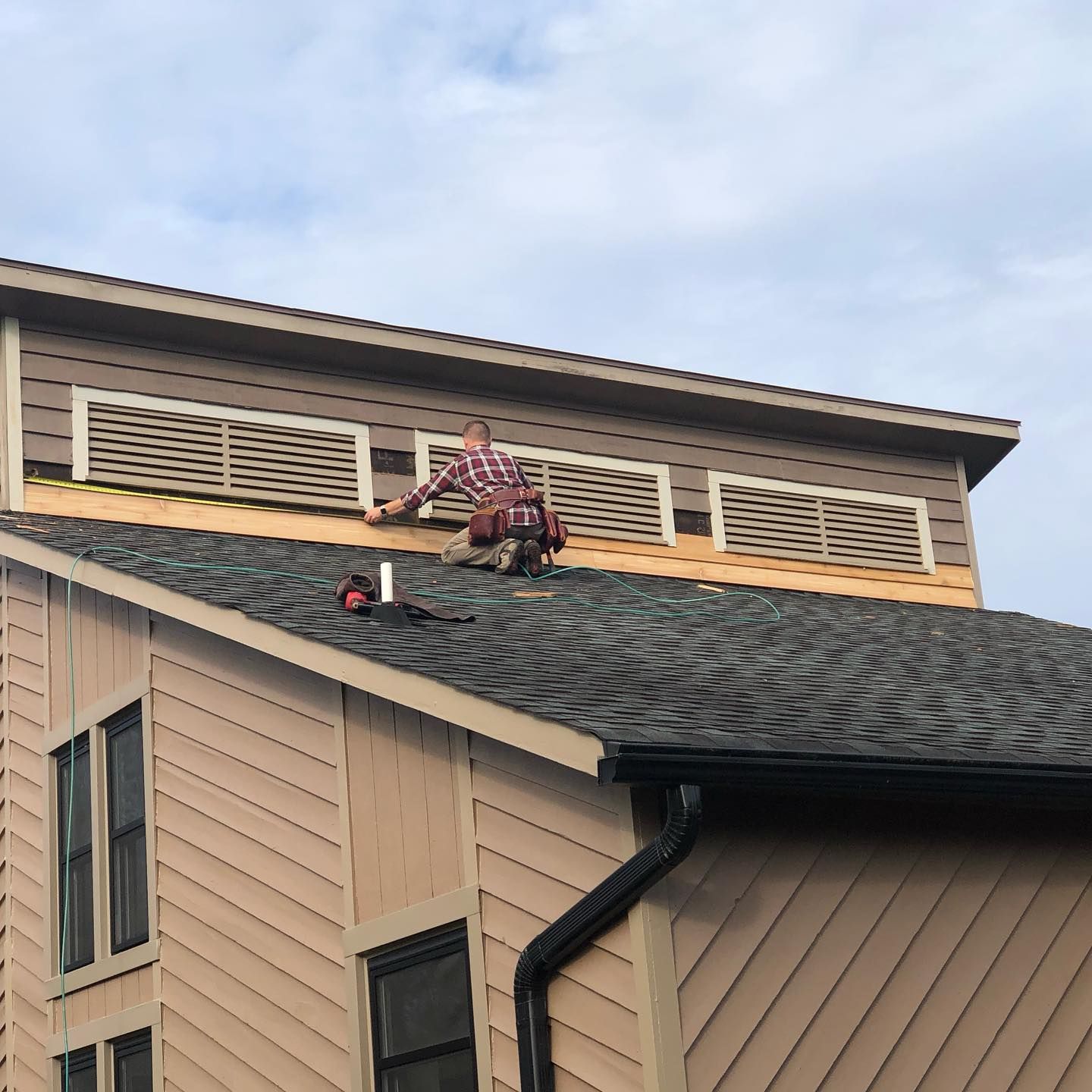 A man is working on the roof of a house.