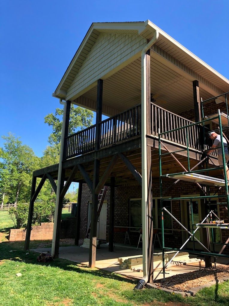 A man is standing on a scaffolding next to a house with a balcony.