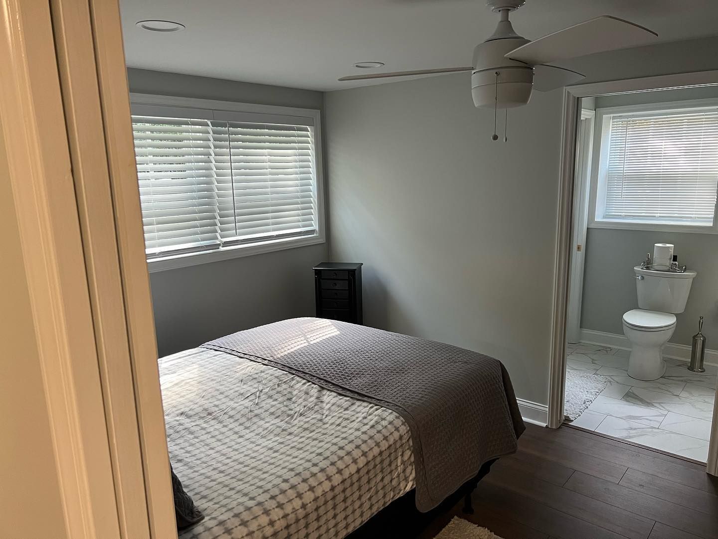 A bedroom with a bed , toilet and ceiling fan.