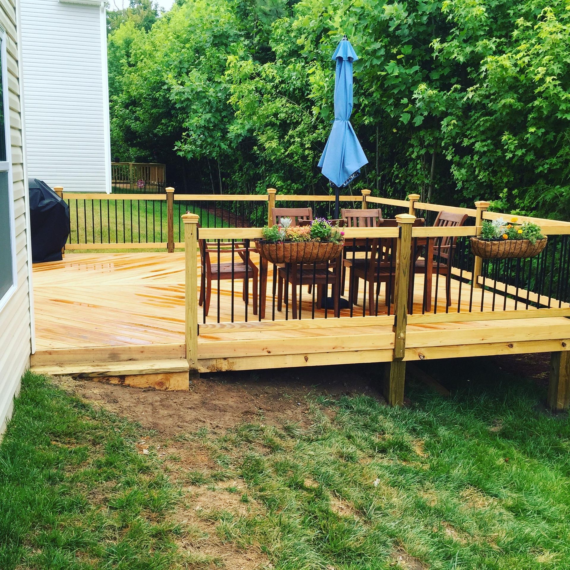 A wooden deck with a table and chairs and a blue umbrella