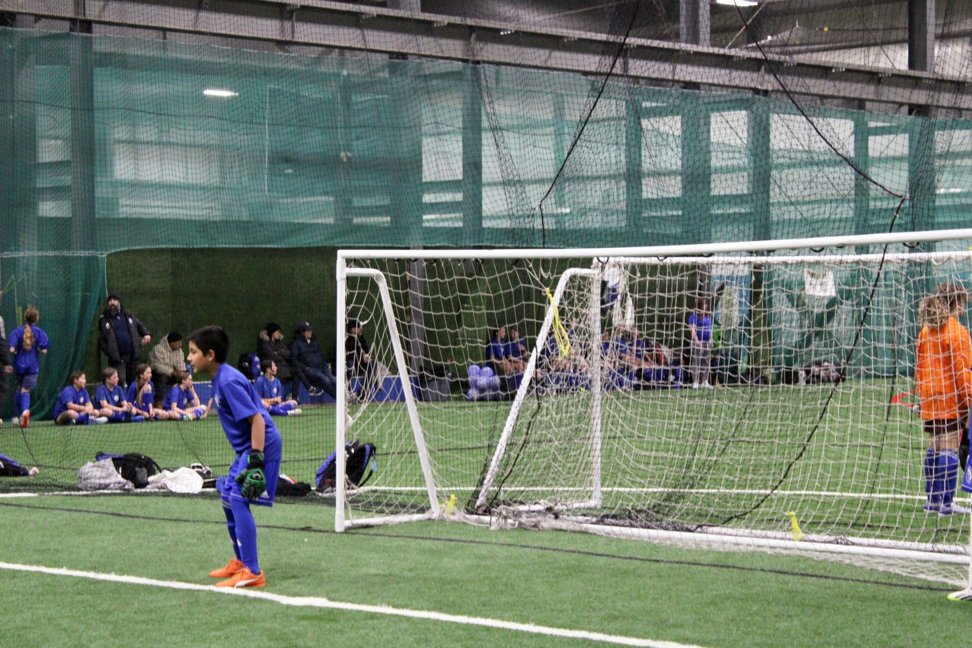 A group of children are playing soccer in an indoor stadium.