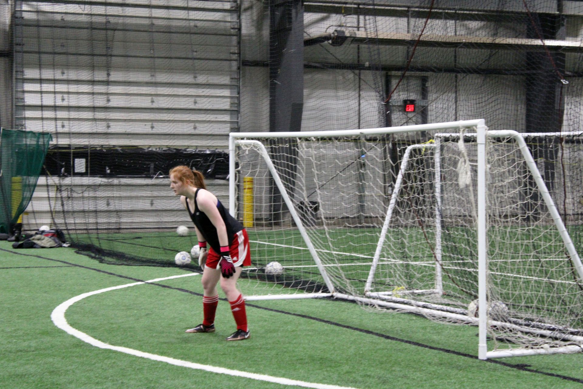 A woman is standing on a soccer field in front of a goal.