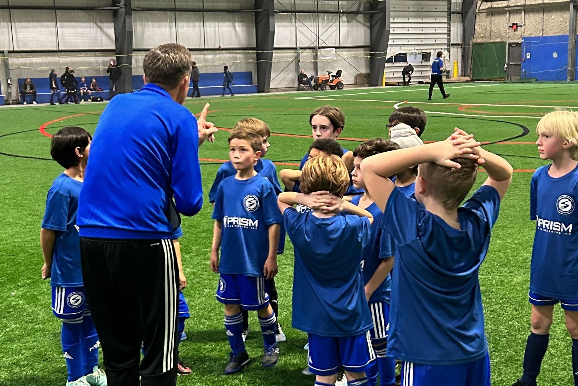 A group of young boys are standing in a huddle on a soccer field.