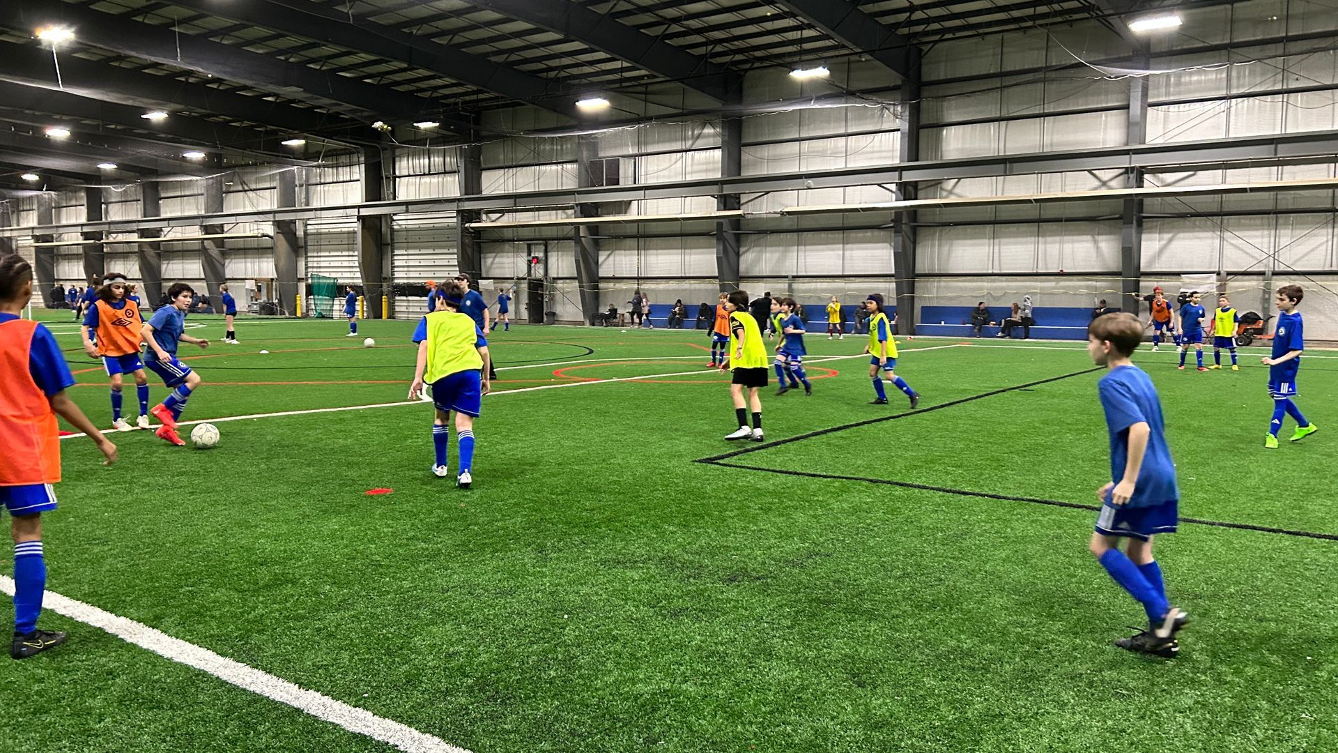 A group of children are playing soccer in an indoor stadium.