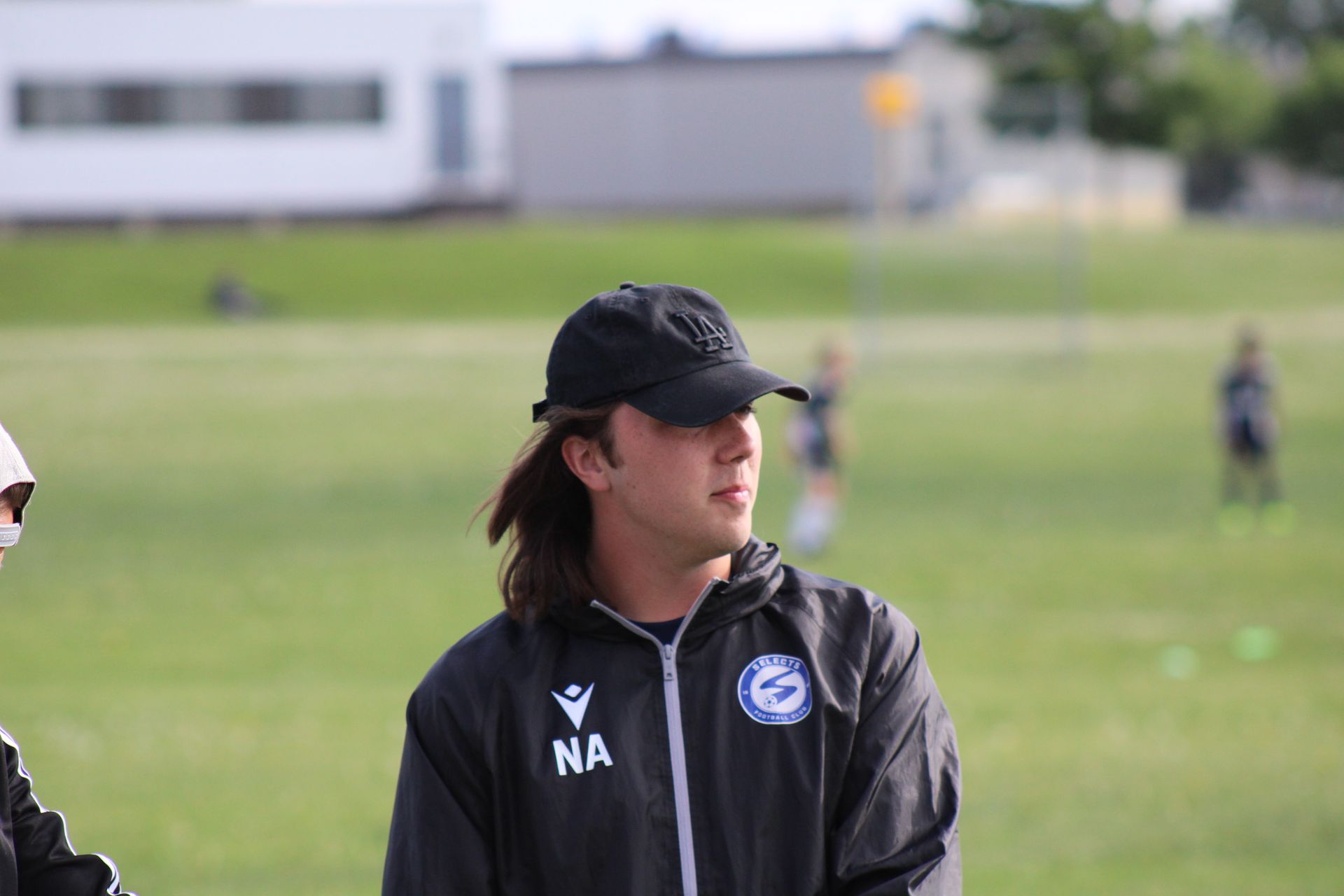 A person wearing a black cap and athletic jacket with 