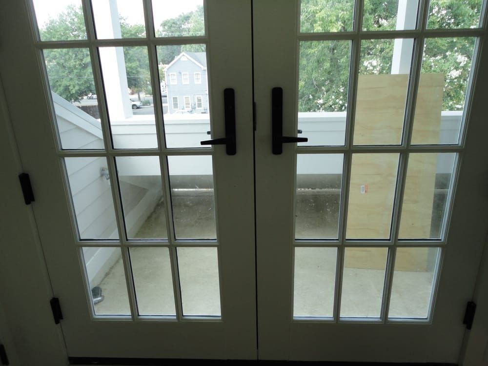 A french door open to a balcony with a house in the background