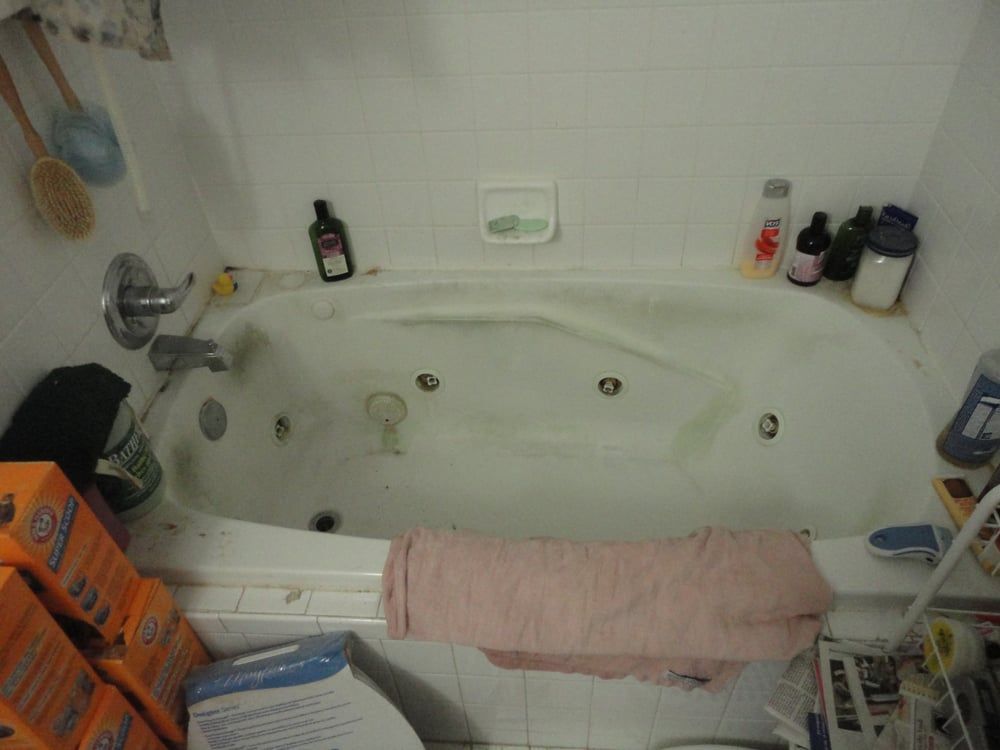 A bathtub in a bathroom with boxes of kleenex on the floor.