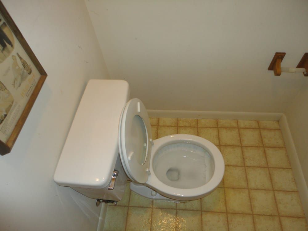 A toilet in a bathroom with the lid up