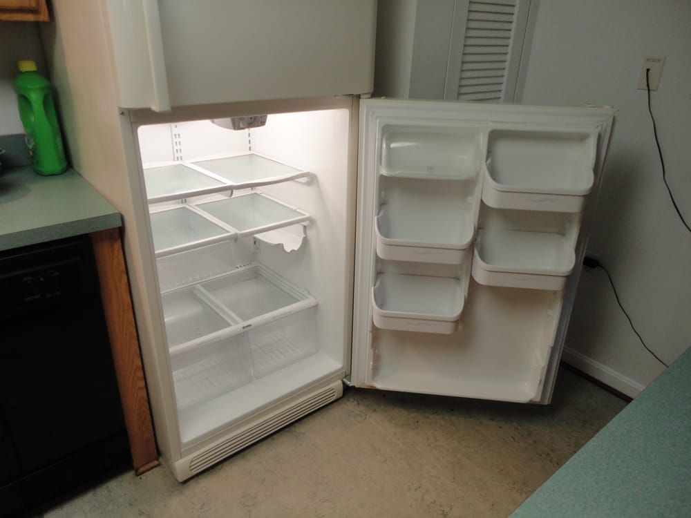 An empty refrigerator with the door open in a kitchen