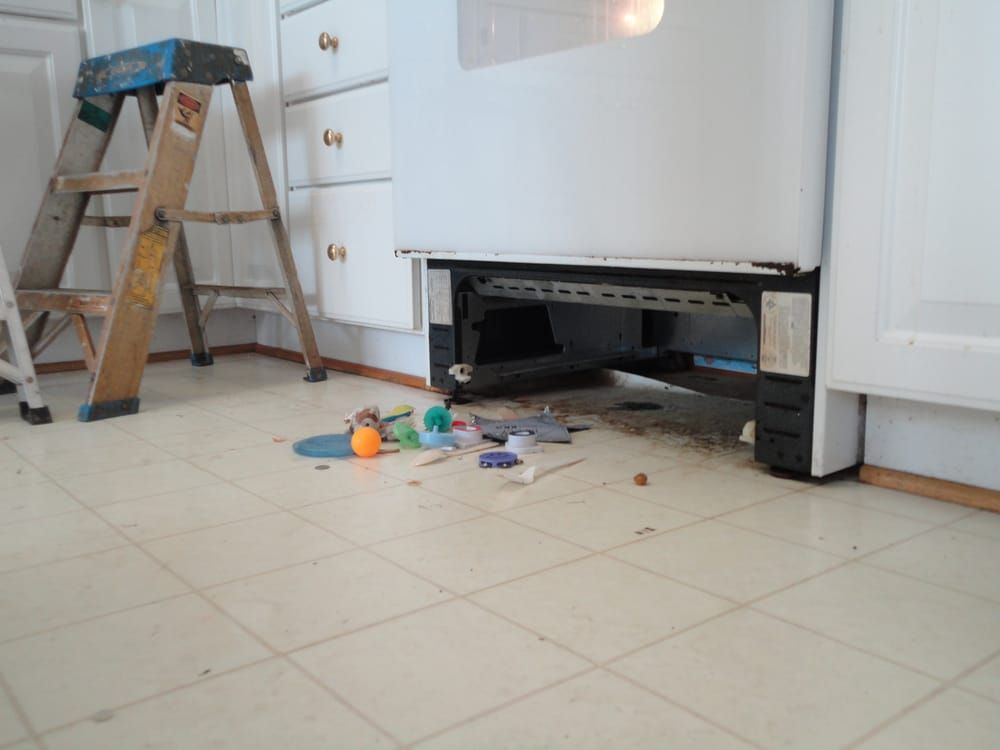A kitchen with a ladder and a broken refrigerator
