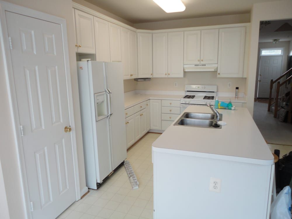 A kitchen with white cabinets and a white refrigerator
