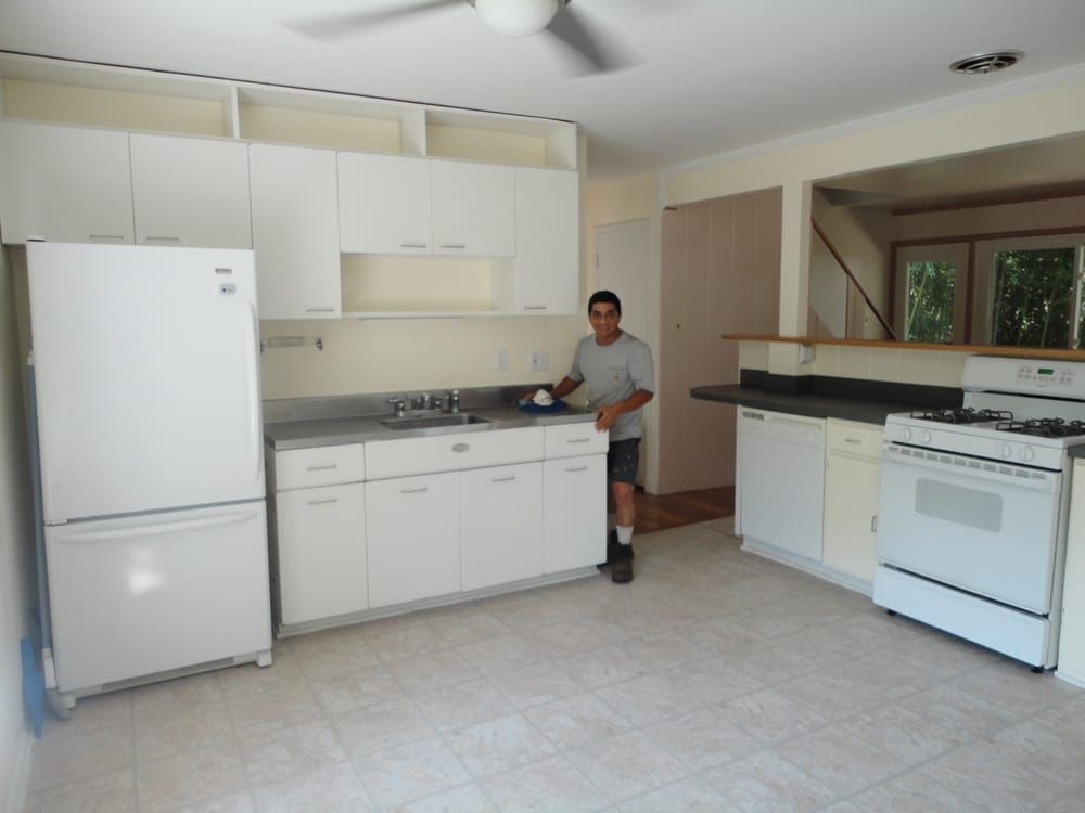A man standing in a kitchen with white cabinets and a stove