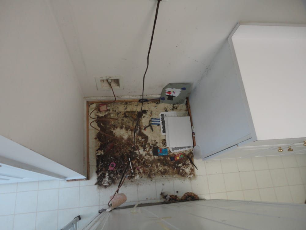 An aerial view of a laundry room with a dirty floor and a refrigerator.