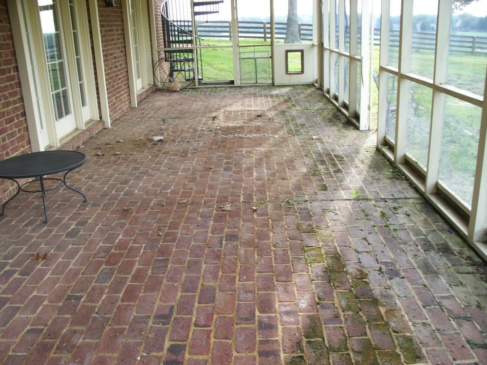 A screened in porch with brick floors and a table