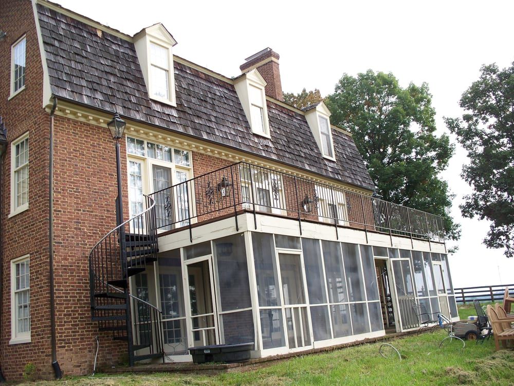 A large brick house with a screened in porch and stairs