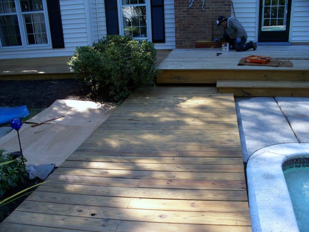 A man is working on a wooden deck next to a pool