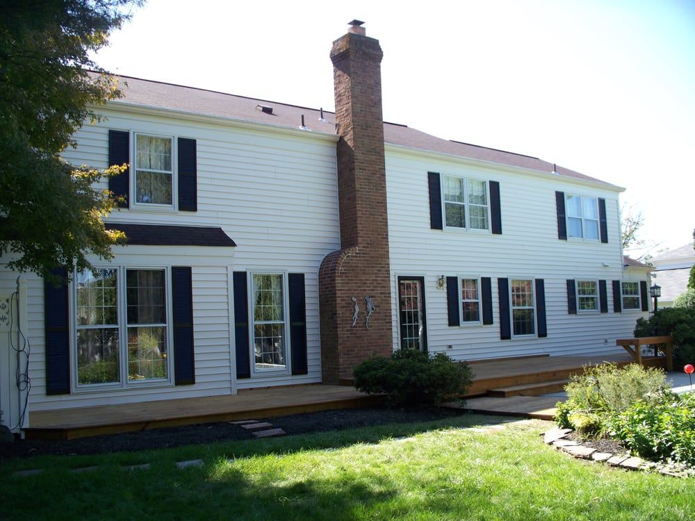 A white house with black shutters and a brick chimney