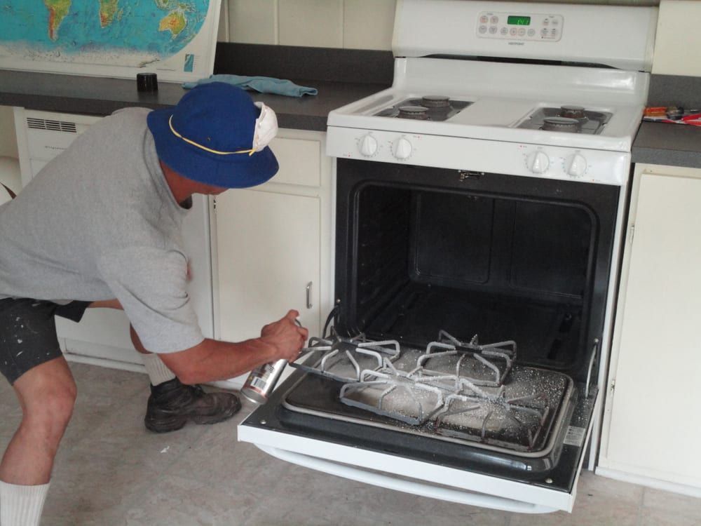 A man in a blue hat is working on a stove