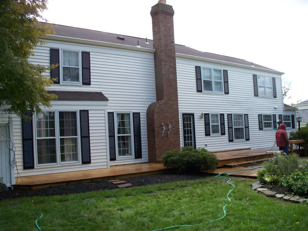 A large white house with black shutters and a brick chimney
