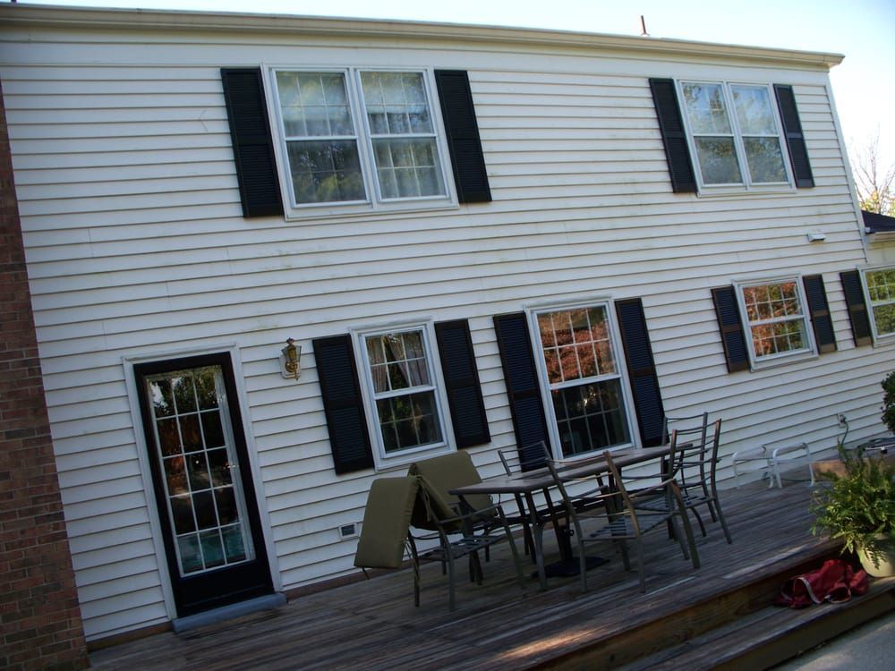 A white house with black shutters and a wooden deck