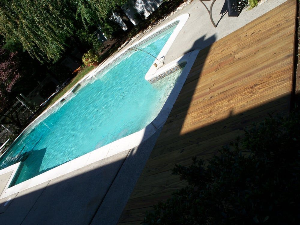 A large swimming pool surrounded by trees and a wooden deck